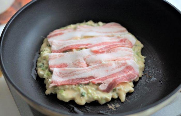 Slab of Osaka-style okonomiyaki cooking in a skillet