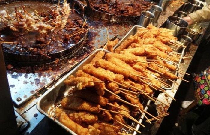 Tubs of fried kushikatsu meat on skewers in sauce