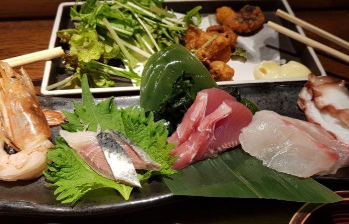 Several plates of meat, sashimi on green leaves, leafy vegetables