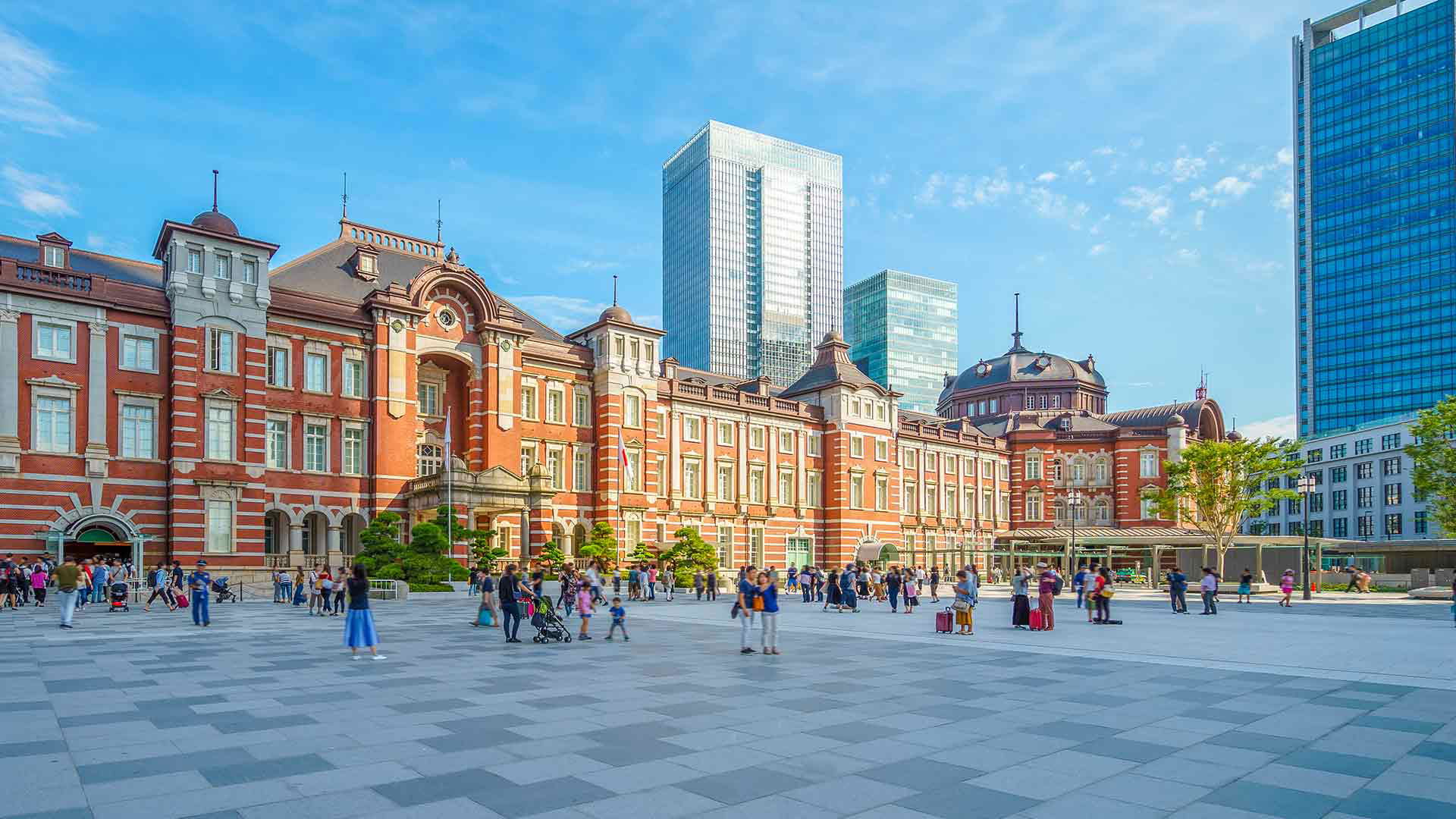Crowded Plaza at Tokyo Station with Modern Skyline