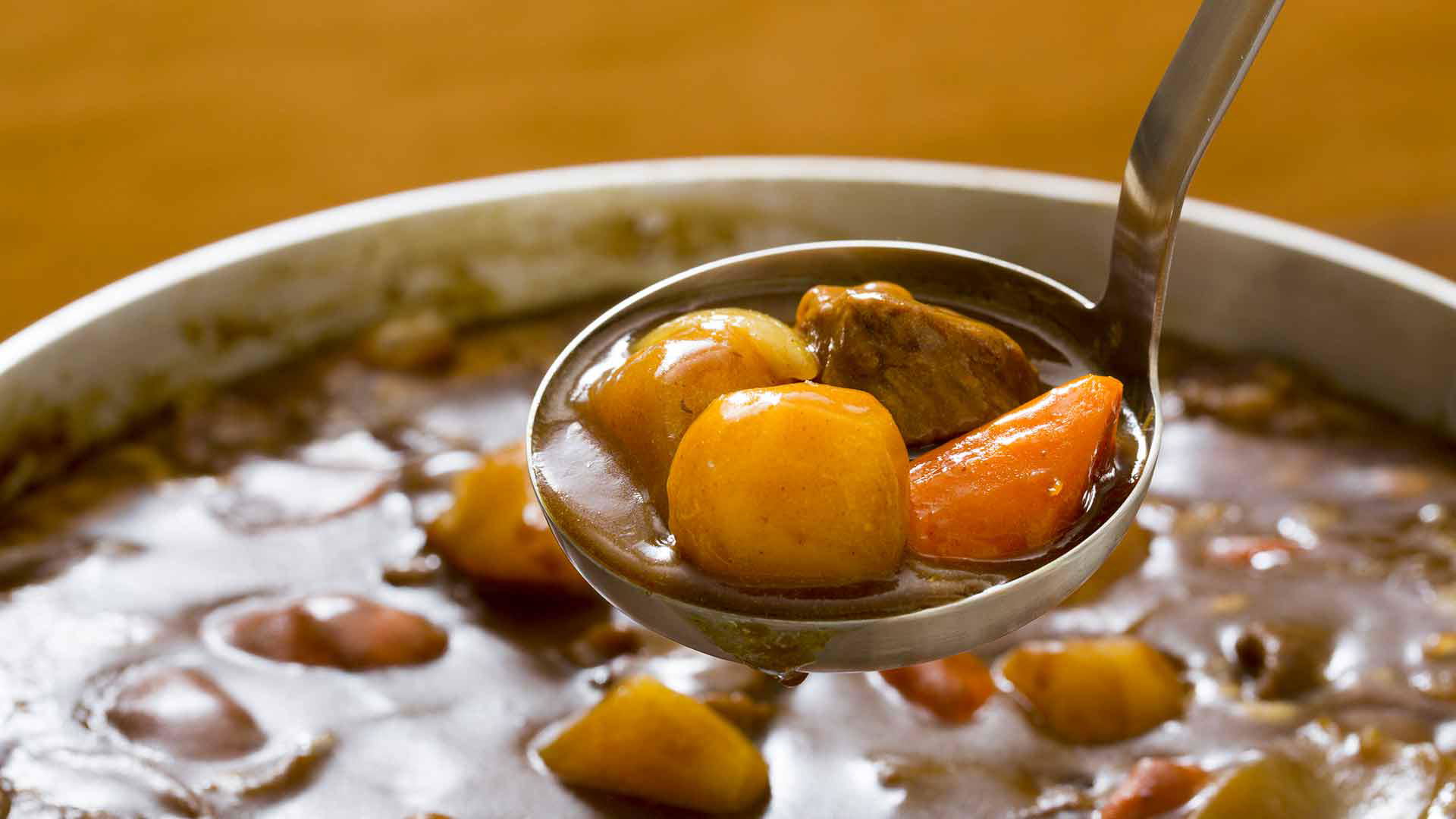 Ladle of hearty beef stew with potatoes and carrots