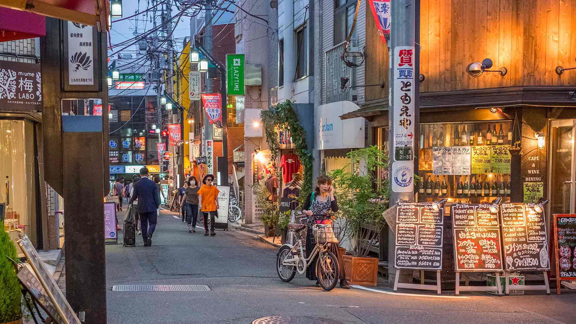 Bustling evening street in Tokyo with shops and bicycles