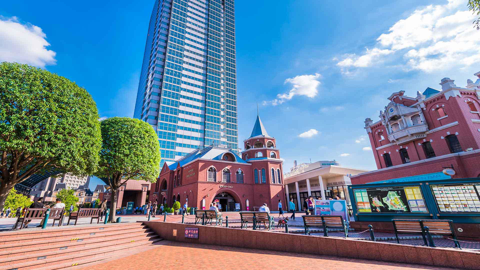 Modern skyscraper beside historic red brick building under blue sky