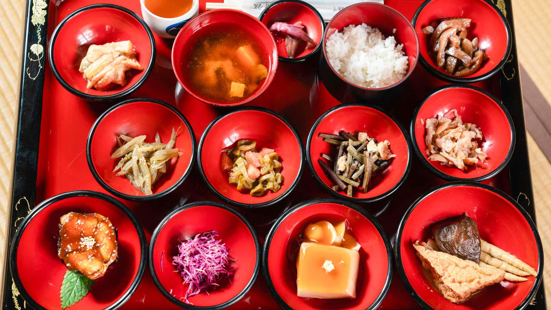 Traditional Japanese Kaiseki meal with various dishes in red lacquer bowls